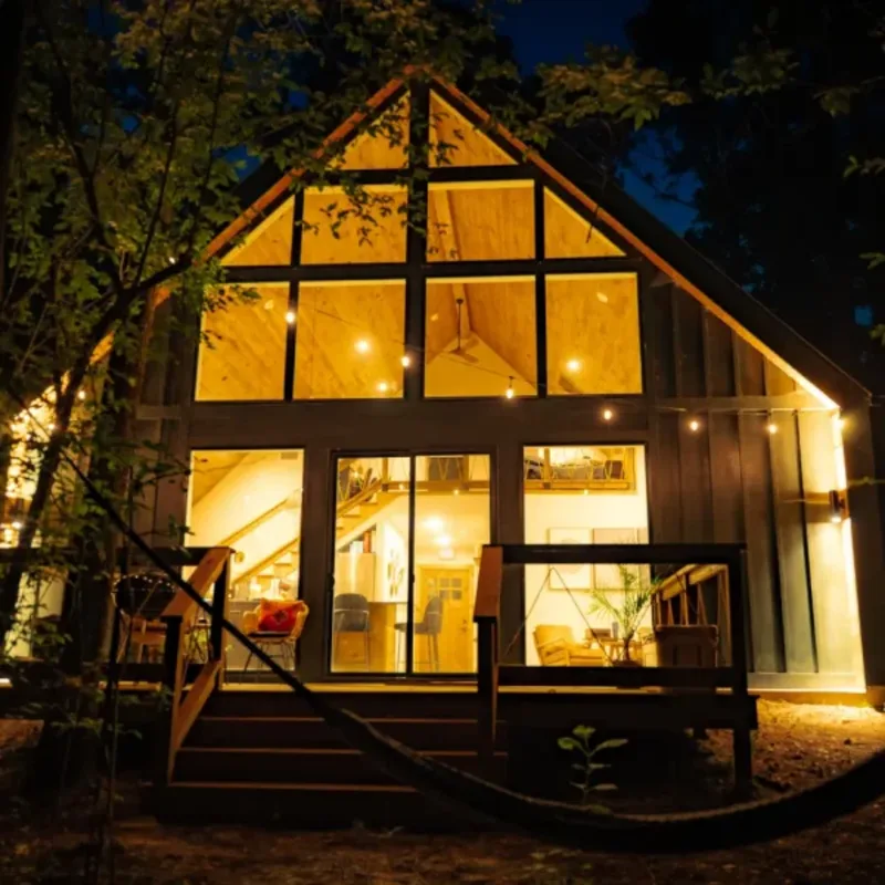 Cardinal cabin glowing at night among the pines