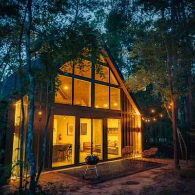 Woodpecker cabin at Lost Forest Cabins, lit from inside at dusk