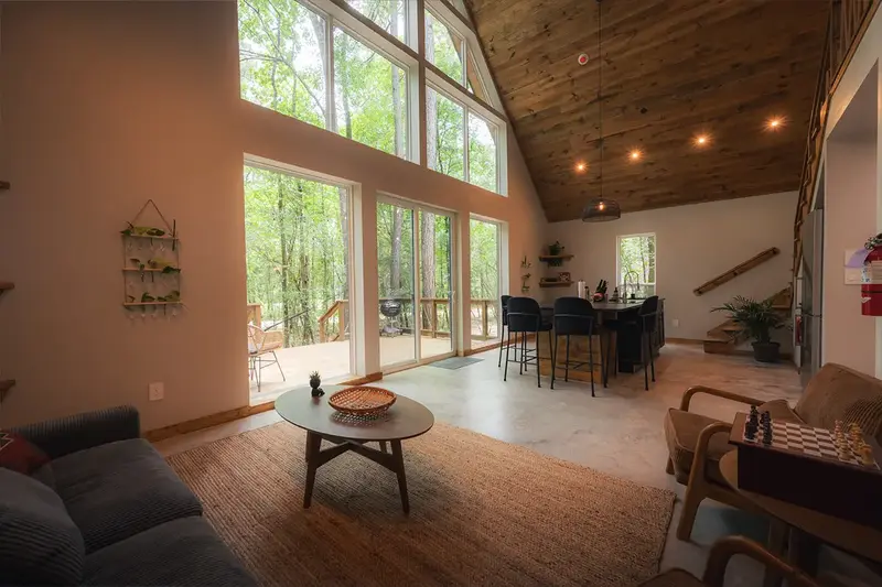 Living area with tall glass doors opening onto the deck, a round coffee table and a chess board
